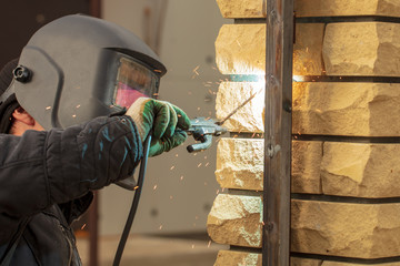 Welder welds metal at the construction site
