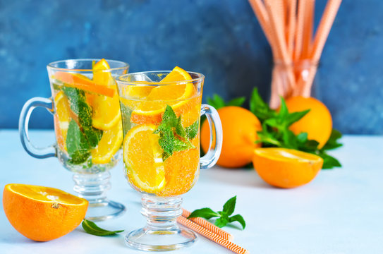 Cold summer drink. Lemonade with mint and orange on a blue background.