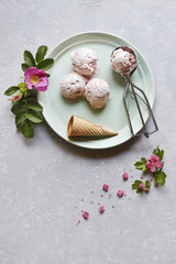 Fototapeta na wymiar Fresh and cold ice-cream in green plate with pink flowers on grey table. Top view, close up on wooden background