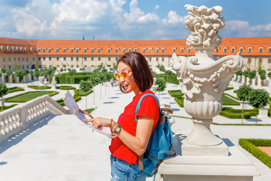 Happy young woman tourist reading map and admiring amazing view of a flower garden in Bratislava, Slovakia
