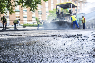 Dump truck and paver machine at work in the steam