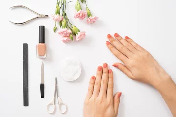 Keuken foto achterwand Manicure Vrouwelijke handen paarse nagellak aanbrengen op houten tafel met handdoek en nagel set