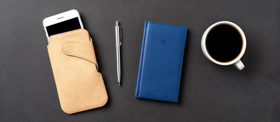 Office desktop with pen, smart phone and notebook