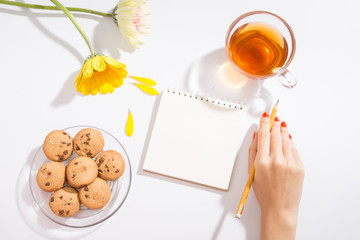 Valentine's day love letter on wooden background. Red velvet heart shape cookies, candy and coffee. Female hands with red nail polish