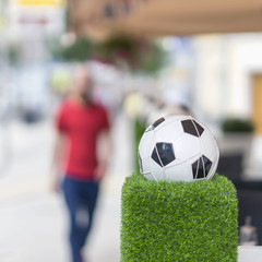 Fototapeta na wymiar Decorative stand in the form of the classic football ball in the net on the green grass. Ornaments of city streets