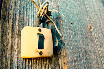 Old Lighting Switch on the wood wall. Close up hand turning on or off on grey light switch with wooden background. Copy space.