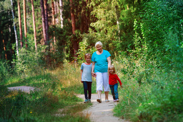 Fototapeta premium happy senior grandmother with kids walk in nature