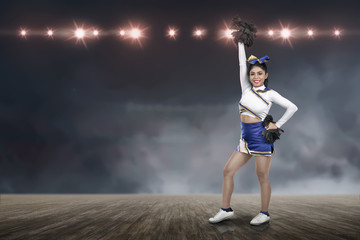 Attractive asian cheerleader holding pom-poms