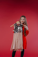 Cute little girl choosing clothes in dressing room.Cute girl choosing a new dress among a lot of clothes in the child fashion store. Sale, gifts, Christmas, holidays; beauty and fashion concept.