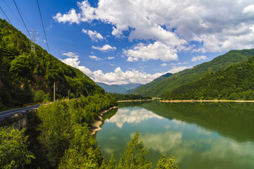 Naklejka na ściany i meble Landscape with Olt river in Romania surrounded by forest and mountains