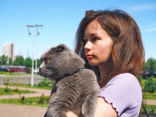 Girl walking with a cat, holding him in her arms