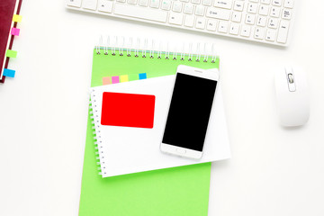 Desktop, keyboard. White smart phone and business card lies on the table,  yellow notebook. White background with copy space, for advertisement, top view