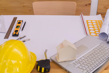 Top view of Blueprints, helmet, laptop, pencil, dividers, smartphone and engineer equipment on working desk.