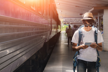 Fototapeta na wymiar Backpacker and hat at the train station and looking on the map for plan to travel, Young traveler with backpack in the railway, Travel concept