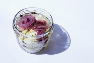 Marinated pickled cheese in oil with black pepper, onions, herbs and spices in glass jar