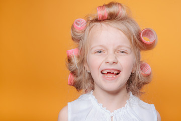Сute little girl on morning.Happy funny child little girl with hair curlers.Portrait of preschooler girl with open mouth without milk tooth