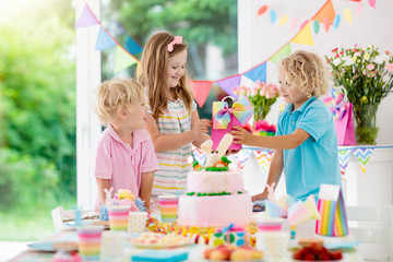 Fototapeta premium Kids birthday party. Children blow cake candles.