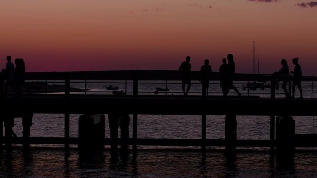 A wide shot of people in the pier and ocean on silhouette