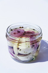 Marinated pickled cheese in oil with black pepper, onions, herbs and spices in glass jar