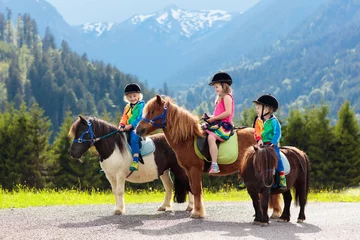 Poster Kinderen rijden pony. Kind te paard in de bergen van de Alpen © famveldman