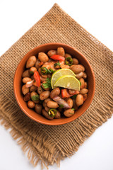 Boiled Peanut Chaat or Chatpata sing dana or shengdana or mungfali. served in a ceramic bowl over moody background