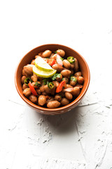Boiled Peanut Chaat or Chatpata sing dana or shengdana or mungfali. served in a ceramic bowl over moody background