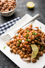 Boiled Peanut Chaat or Chatpata sing dana or shengdana or mungfali. served in a ceramic bowl over moody background