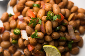 Boiled Peanut Chaat or Chatpata sing dana or shengdana or mungfali. served in a ceramic bowl over moody background