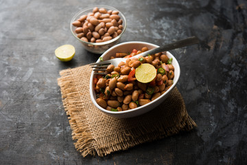 Boiled Peanut Chaat or Chatpata sing dana or shengdana or mungfali. served in a ceramic bowl over moody background