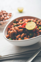 Boiled Peanut Chaat or Chatpata sing dana or shengdana or mungfali. served in a ceramic bowl over moody background