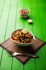 Boiled Peanut Chaat or Chatpata sing dana or shengdana or mungfali. served in a ceramic bowl over moody background
