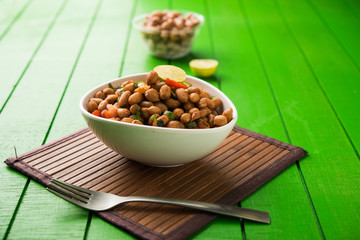 Boiled Peanut Chaat or Chatpata sing dana or shengdana or mungfali. served in a ceramic bowl over moody background