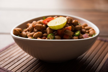 Boiled Peanut Chaat or Chatpata sing dana or shengdana or mungfali. served in a ceramic bowl over moody background