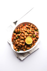 Boiled Peanut Chaat or Chatpata sing dana or shengdana or mungfali. served in a ceramic bowl over moody background