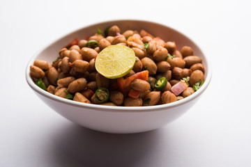 Boiled Peanut Chaat or Chatpata sing dana or shengdana or mungfali. served in a ceramic bowl over moody background
