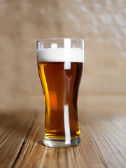 A glass of cold beer or ale on a wooden background