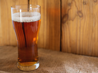 A glass of cold beer or ale on a wooden background