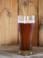 A glass of cold beer or ale on a wooden background