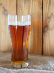A glass of cold beer or ale on a wooden background