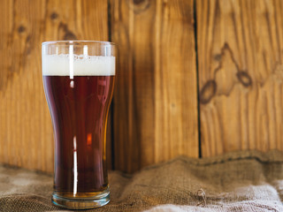 A glass of cold beer or ale on a wooden background