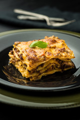 Traditional Lasagna With Minced Beef, Bolognese Sauce and Basil on Dark Plate. Italian Cuisine.