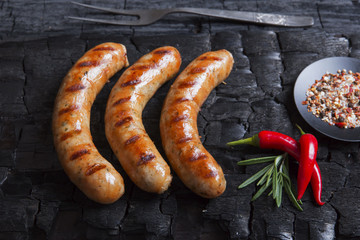 Grilled sausages on a black background of charcoal. Barbecue grill