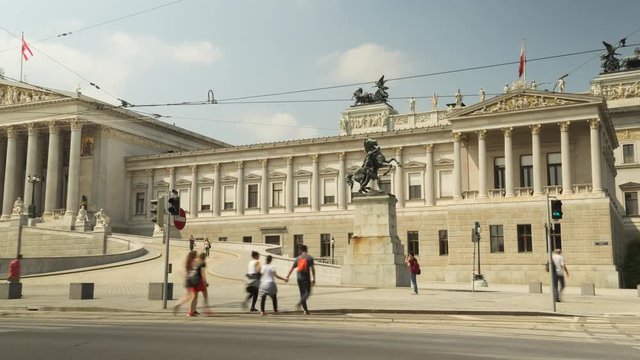 Camera pans left across Vienna's Parliament building in summer sunshine.