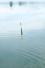 Fishing rod, fishing pole with a cork or float on the line on the lake background