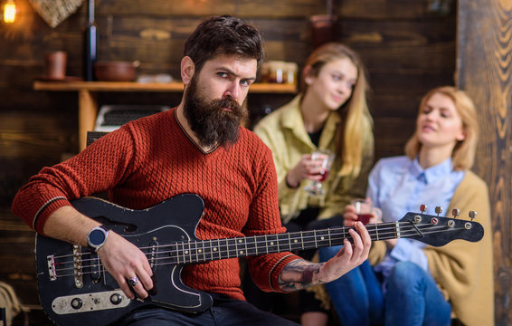 Guitarist rehearsing new show. Bearded man entertaining his wife and daughter with lovely tunes. Rock musician on vacation with family in countryside. Man with stylish hipster beard playing guitar