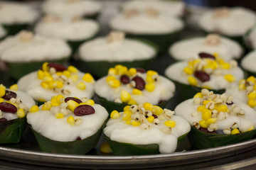 Thai dessert ,Thai pudding with coconut, Red bean, corn, Taro topping on top in the banana leaf