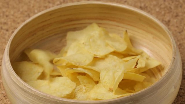 Close up of potato chips pouting into bowl. No sound.