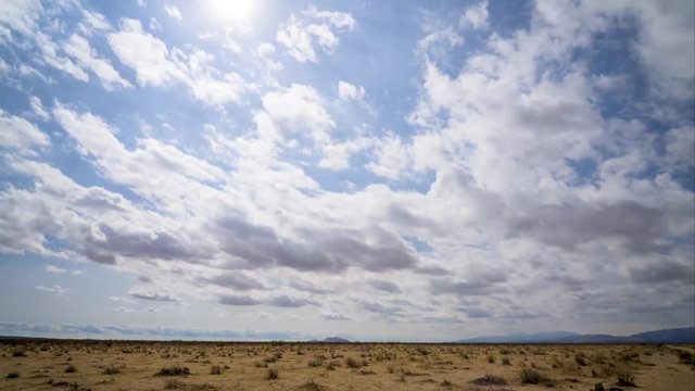 Sun shines over desert on cloudy day, Time Lapse