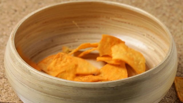 Close up of nacho chips falling into bowl. No sound.