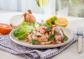 Spicy Tuna Salad onion and tomatoes in plate put on tabal , Thailand cuisine.